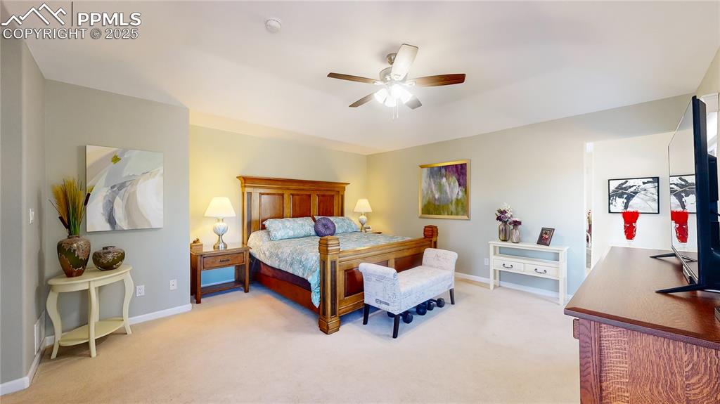 Image 14 of 34: Bedroom with light colored carpet, baseboards, and a ceiling fan
