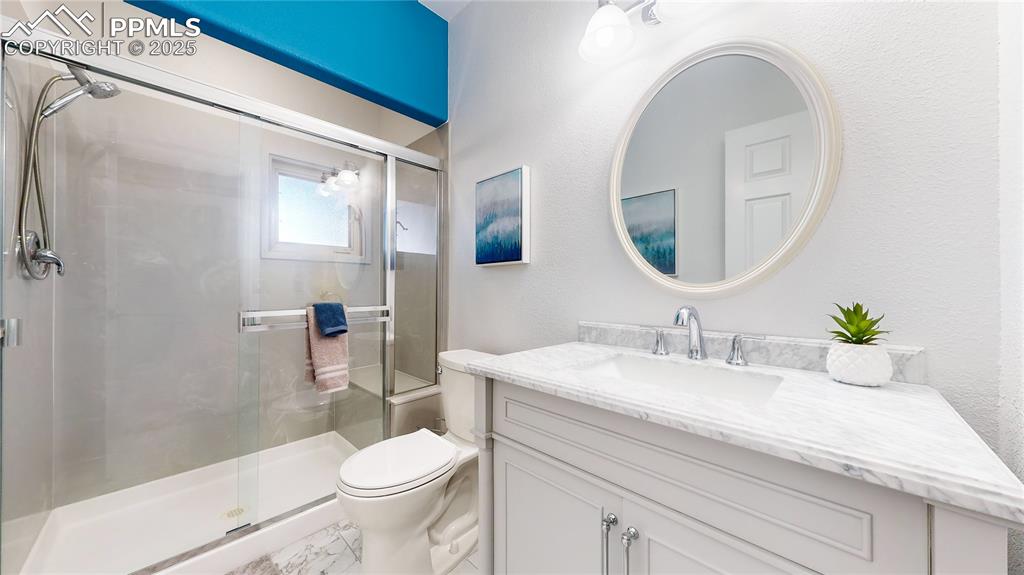 Image 16 of 34: Full bathroom with toilet, a stall shower, vanity, and marble finish floors