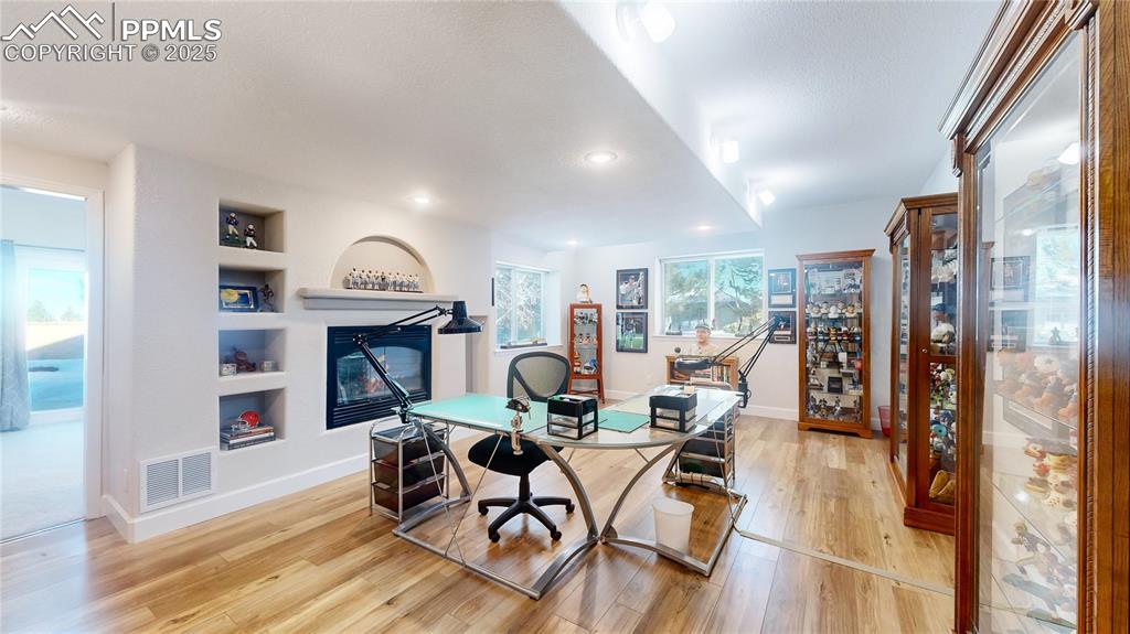 Image 17 of 34: Office with light wood-type flooring, baseboards, built in shelves, and rec
