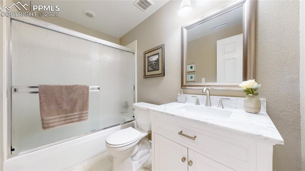 Image 19 of 34: Bathroom with vanity, toilet, a textured wall, and shower / bath combinatio