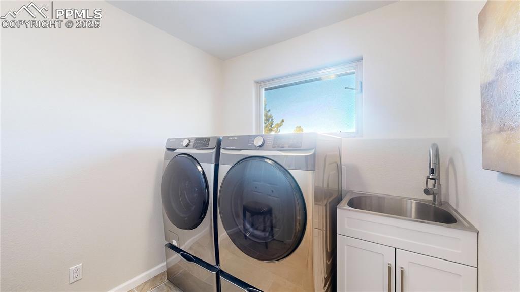Image 21 of 34: Laundry area with cabinet space, washer and clothes dryer, and baseboards