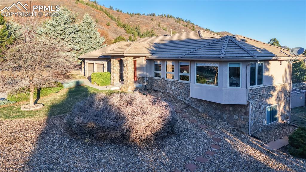 Image 22 of 34: View of front of home featuring stone siding, a tile roof, a mountain view,
