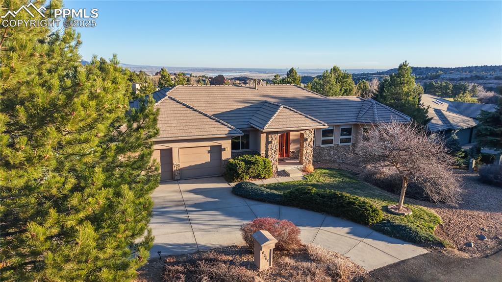 Image 23 of 34: Ranch-style house featuring concrete driveway, a garage, stone siding, a ti