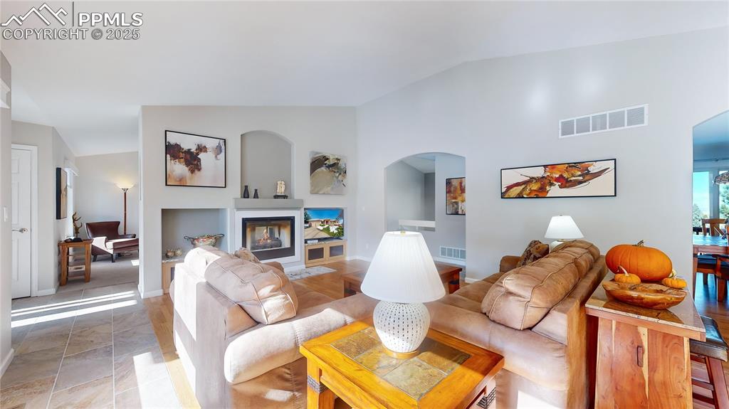 Image 4 of 34: Living area with arched walkways, vaulted ceiling, and baseboards