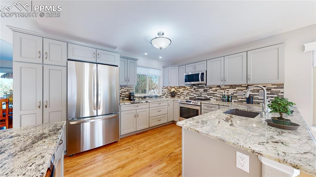 Image 7 of 34: Kitchen featuring appliances with stainless steel finishes, a sink, a penin