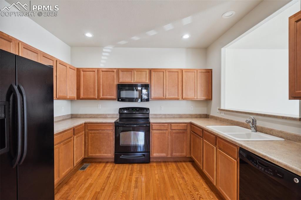 Image 10 of 28: Kitchen featuring black appliances, light countertops, light wood-style flo
