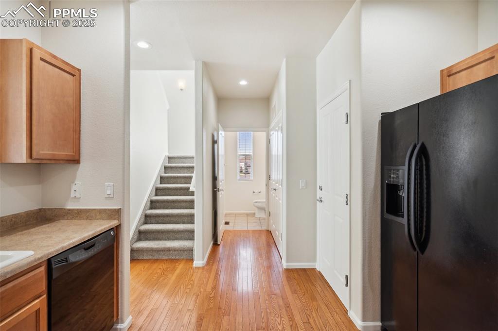 Image 14 of 28: Kitchen featuring black appliances, light wood-style floors, light countert