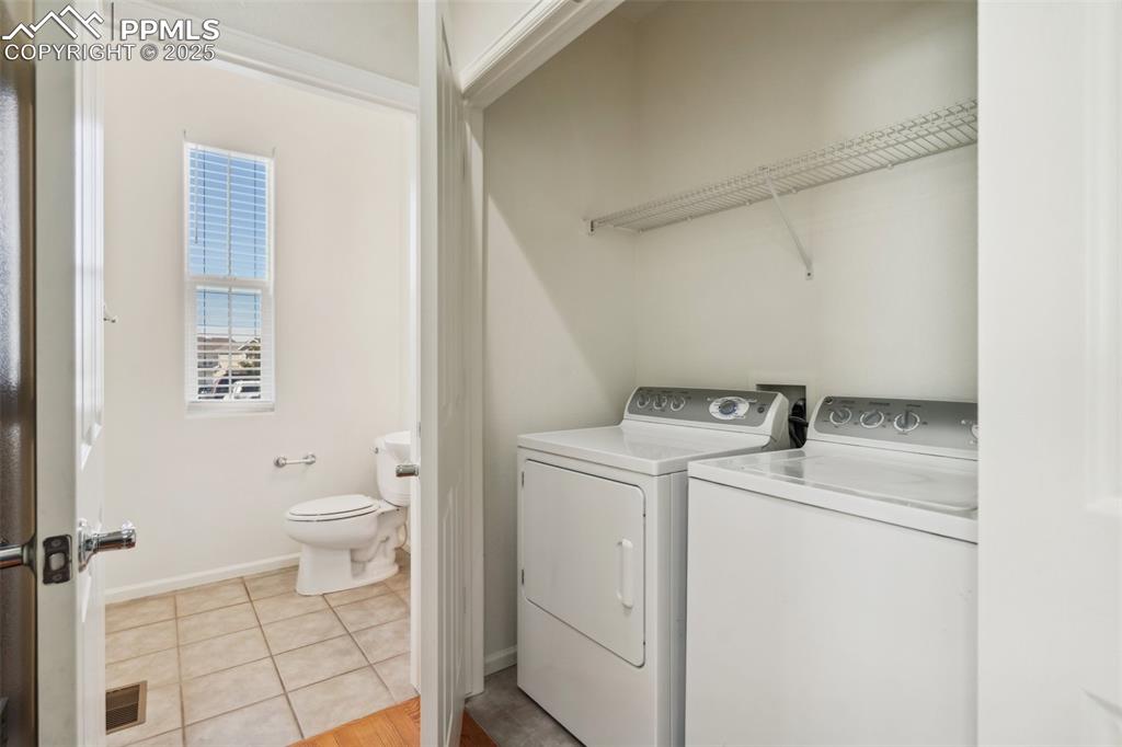 Image 17 of 28: Washroom with washing machine and clothes dryer and light tile patterned fl