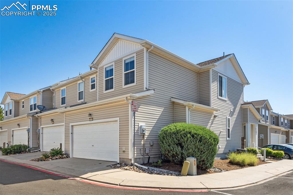 Image 2 of 28: View of side of home featuring a garage, a residential view, and driveway