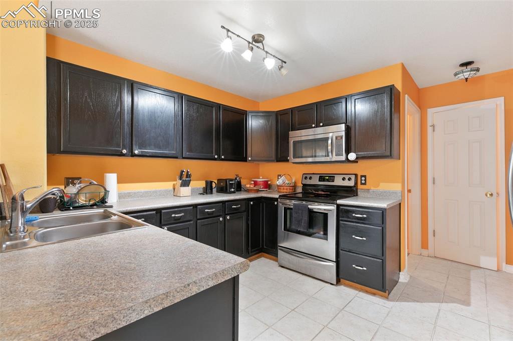 Image 11 of 29: Kitchen featuring stainless steel appliances, light tile patterned flooring