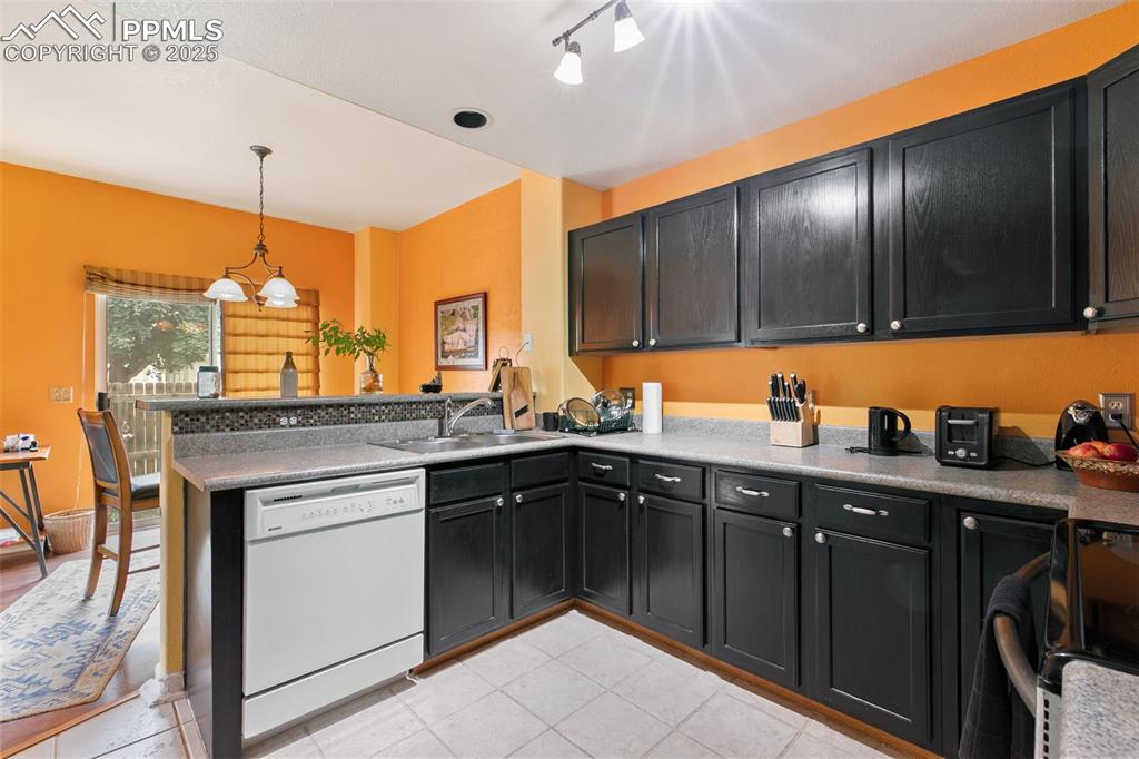 Image 13 of 29: Kitchen with a peninsula, white dishwasher, black range, dark cabinetry, an