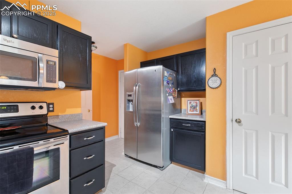 Image 14 of 29: Kitchen featuring stainless steel appliances, light countertops, dark cabin