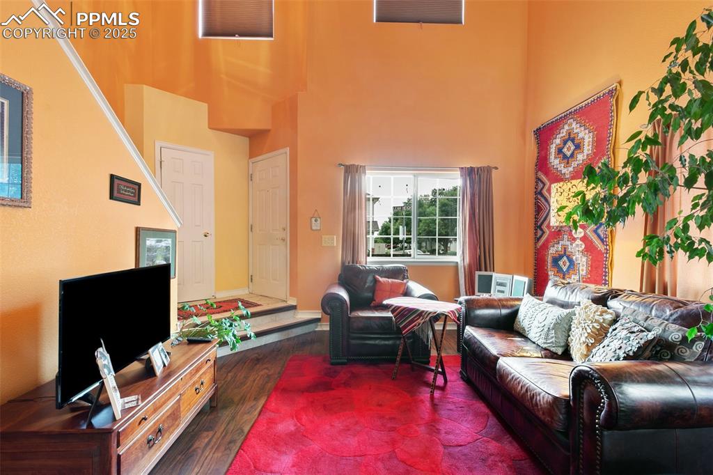 Image 8 of 29: Living area with dark wood-type flooring and a high ceiling