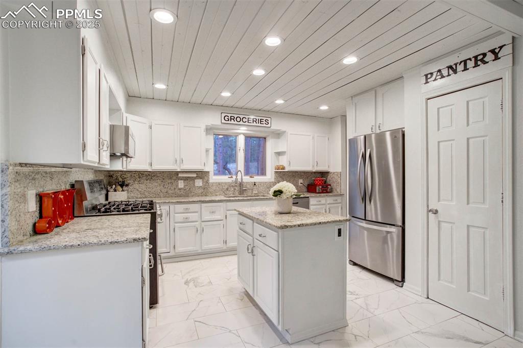 Image 12 of 48: Kitchen featuring white cabinets, appliances with stainless steel finishes,