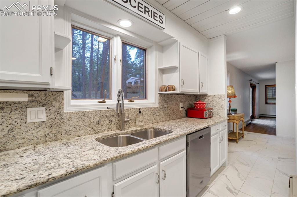 Image 13 of 48: Kitchen with open shelves, tasteful backsplash, white cabinetry, light marb