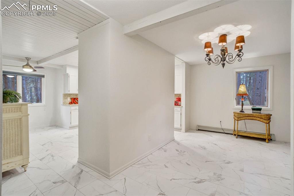 Image 16 of 48: Dining area featuring beam ceiling, light marble finish flooring, a chandel
