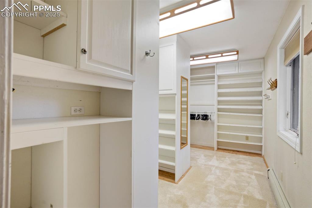 Image 20 of 48: Walk in closet featuring baseboard heating and light colored carpet
