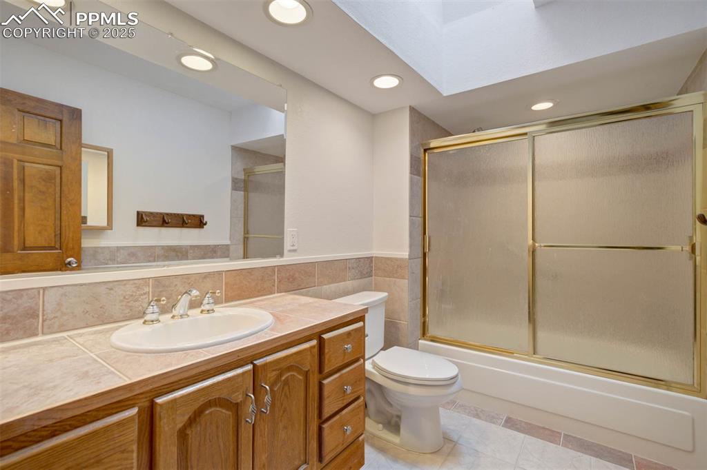 Image 23 of 48: Bathroom with bath / shower combo with glass door, recessed lighting, vanit