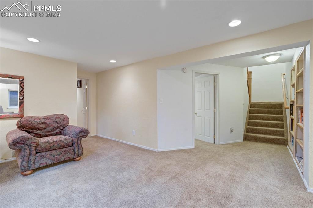 Image 25 of 48: Sitting room featuring light colored carpet, recessed lighting, and stairs