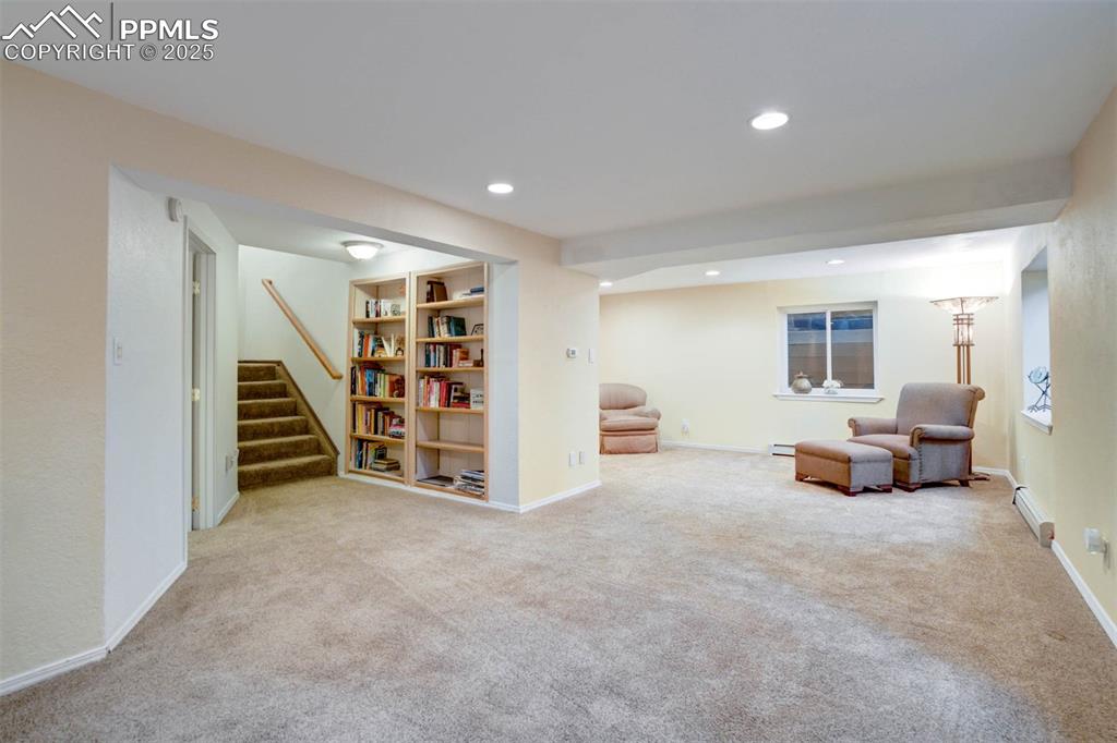 Image 26 of 48: Living area with light colored carpet, recessed lighting, stairs, and a bas