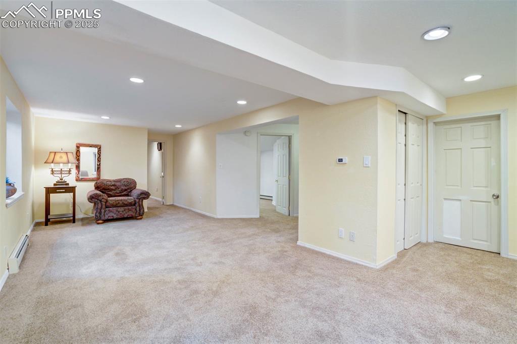 Image 27 of 48: Living area with recessed lighting, light colored carpet, and a baseboard h