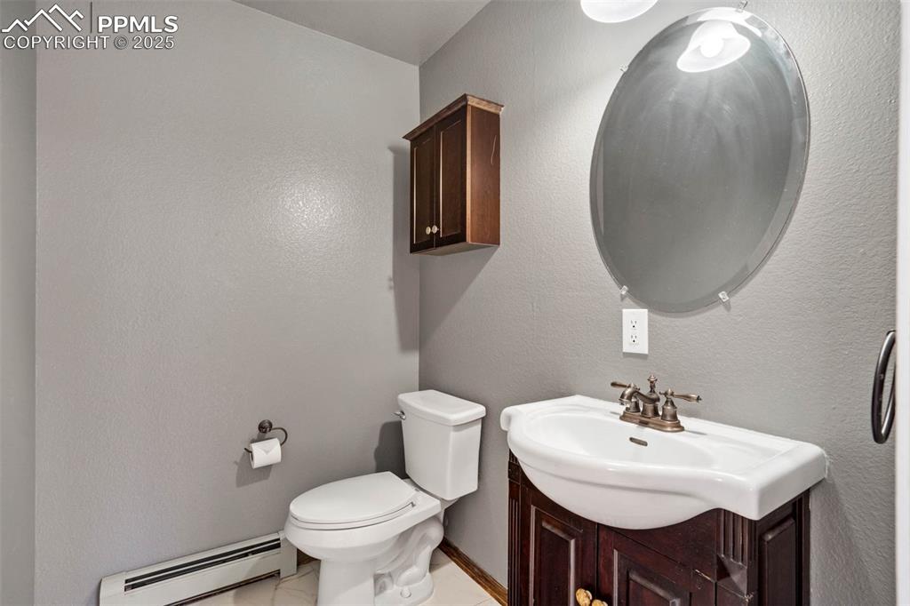 Image 28 of 48: Half bathroom featuring a baseboard radiator, vanity, and a textured wall