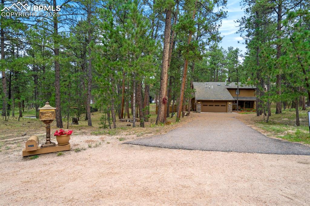 Image 39 of 48: Rustic home with a shingled roof and driveway