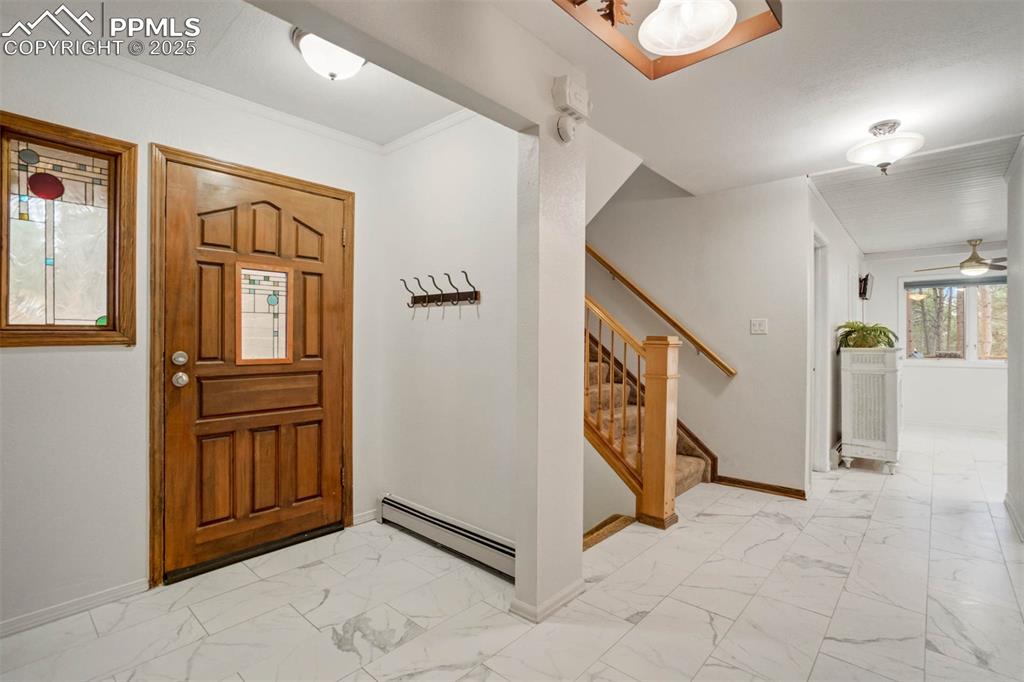 Image 4 of 48: Entryway featuring light marble finish flooring, stairway, crown molding, a