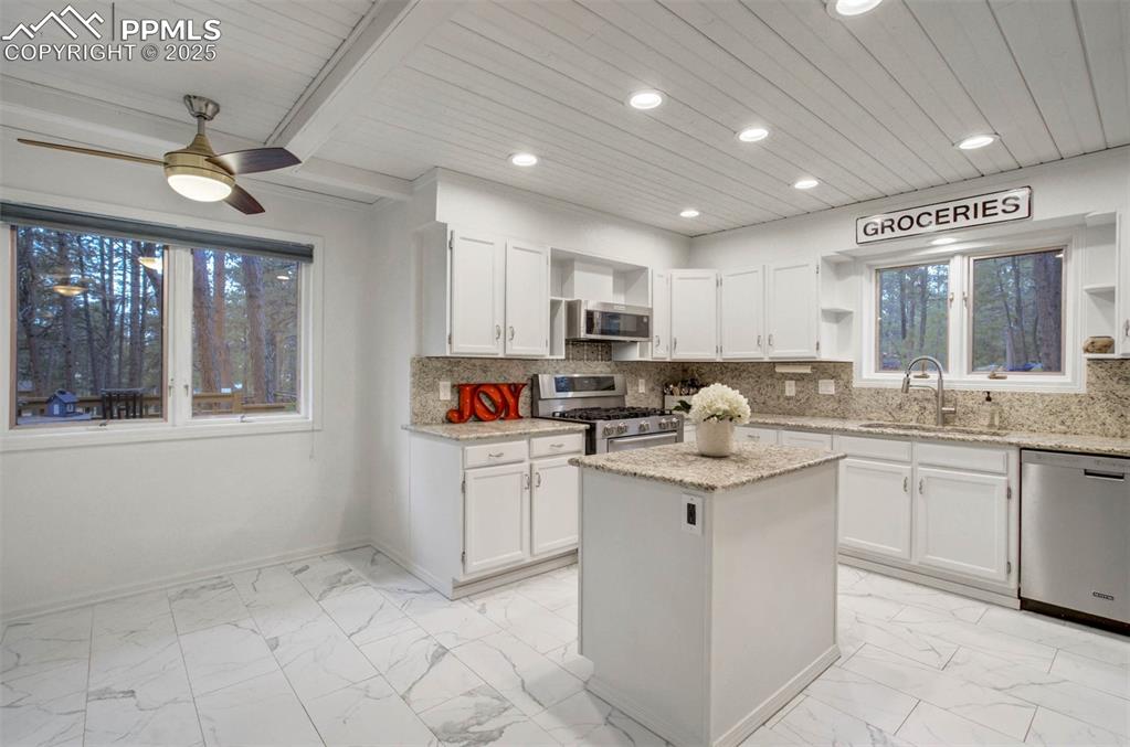 Image 43 of 48: Kitchen featuring open shelves, decorative backsplash, white cabinetry, app