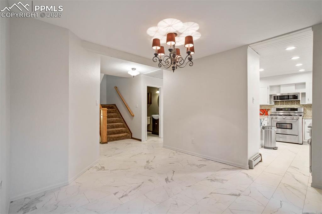 Image 44 of 48: Unfurnished dining area featuring light marble finish flooring, a chandelie