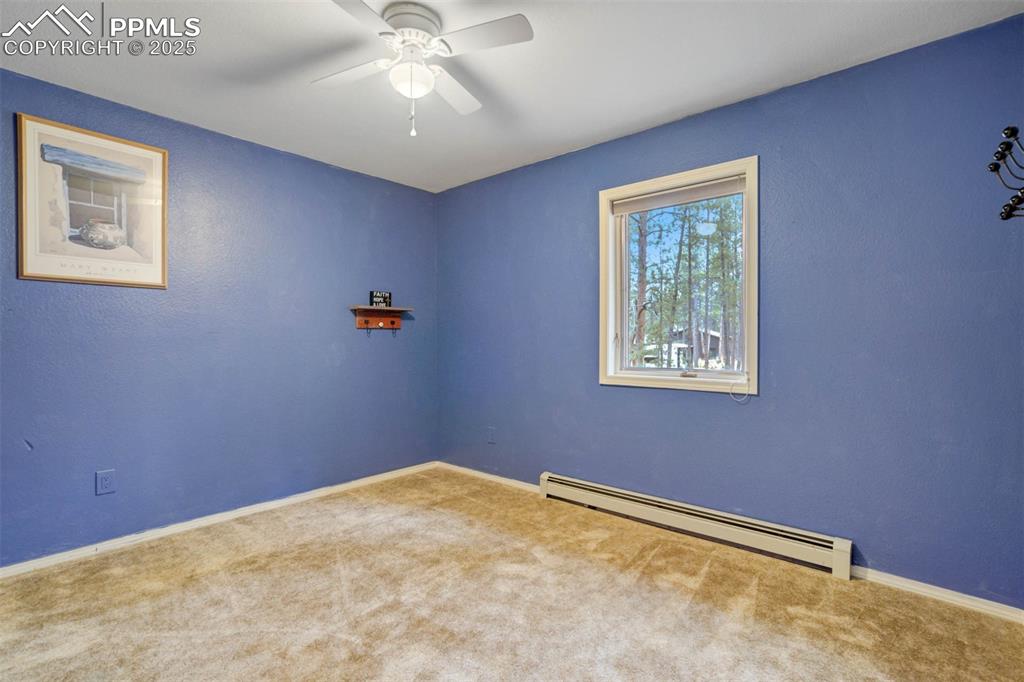 Image 46 of 48: Carpeted empty room with a baseboard radiator, a ceiling fan, and a texture