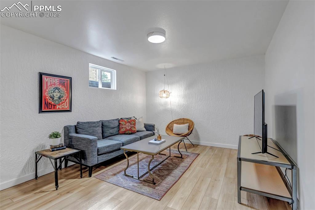 Image 19 of 35: Living area featuring a textured wall, light wood-type flooring, and basebo