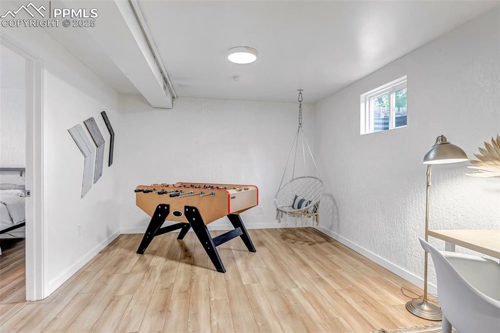 Image 22 of 35: Playroom with light wood-type flooring, baseboards, and a textured wall
