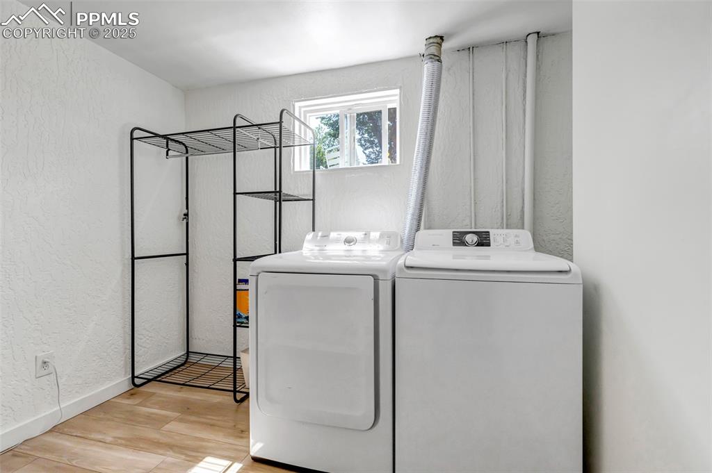 Image 25 of 35: Laundry area featuring a textured wall, light wood finished floors, and was