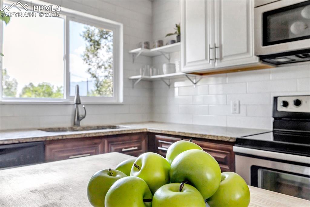 Image 6 of 35: Kitchen with stainless steel appliances, tasteful backsplash, light stone c