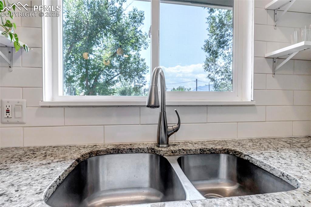 Image 8 of 35: Kitchen view of open shelves, light stone counters, and tasteful backsplash