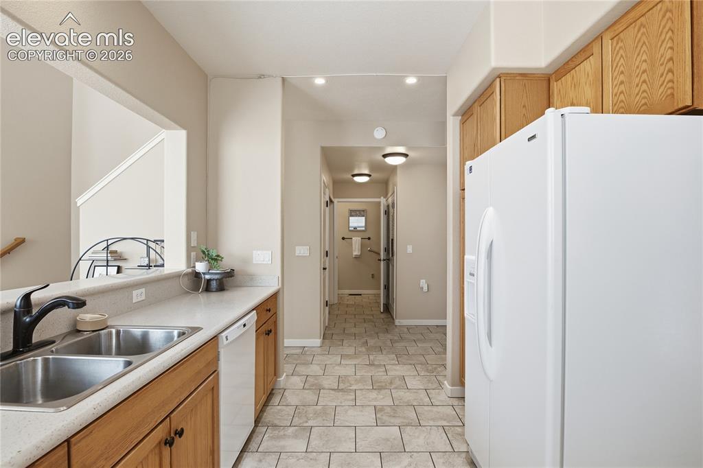 Image 11 of 27: Kitchen featuring wood cabinetry, light-toned countertops, a double basin s