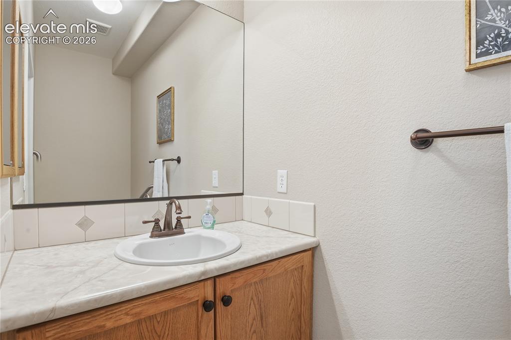 Image 13 of 27: Built-in vanity with a single basin sink, bronze-finish faucet, and wood-fi