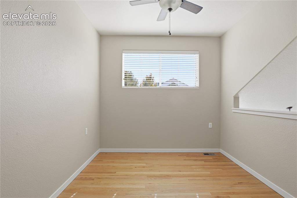 Image 20 of 27: Wood-finish flooring, overhead ceiling fan, and a single window with horizo