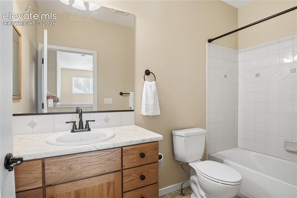 Image 24 of 27: Bathroom featuring a wood-finish vanity with a built-in sink, a stone-look 