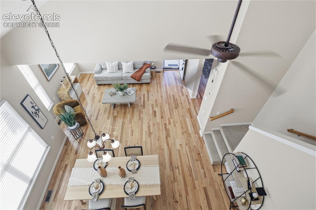 Image 25 of 27: Vaulted ceiling with a ceiling fan, wood-finish flooring, two large windows