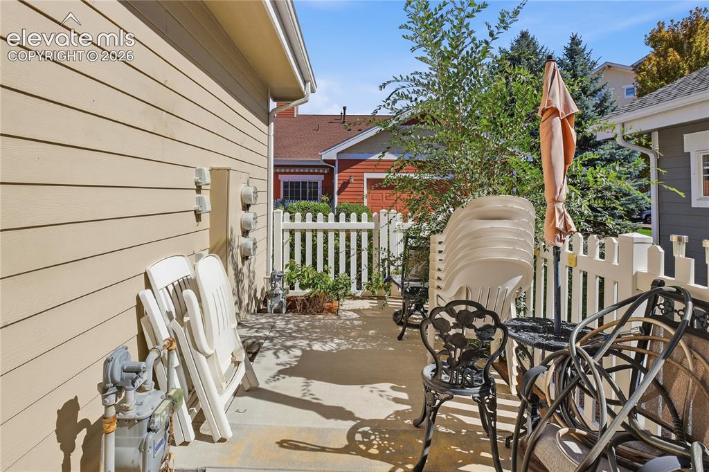 Image 26 of 27: Picket fence enclosing a concrete patio area, featuring a light-colored sid