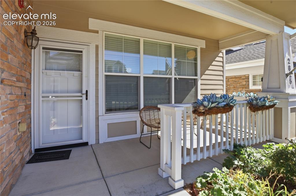 Image 3 of 27: Covered front porch featuring a stacked stone exterior, white railing, and
