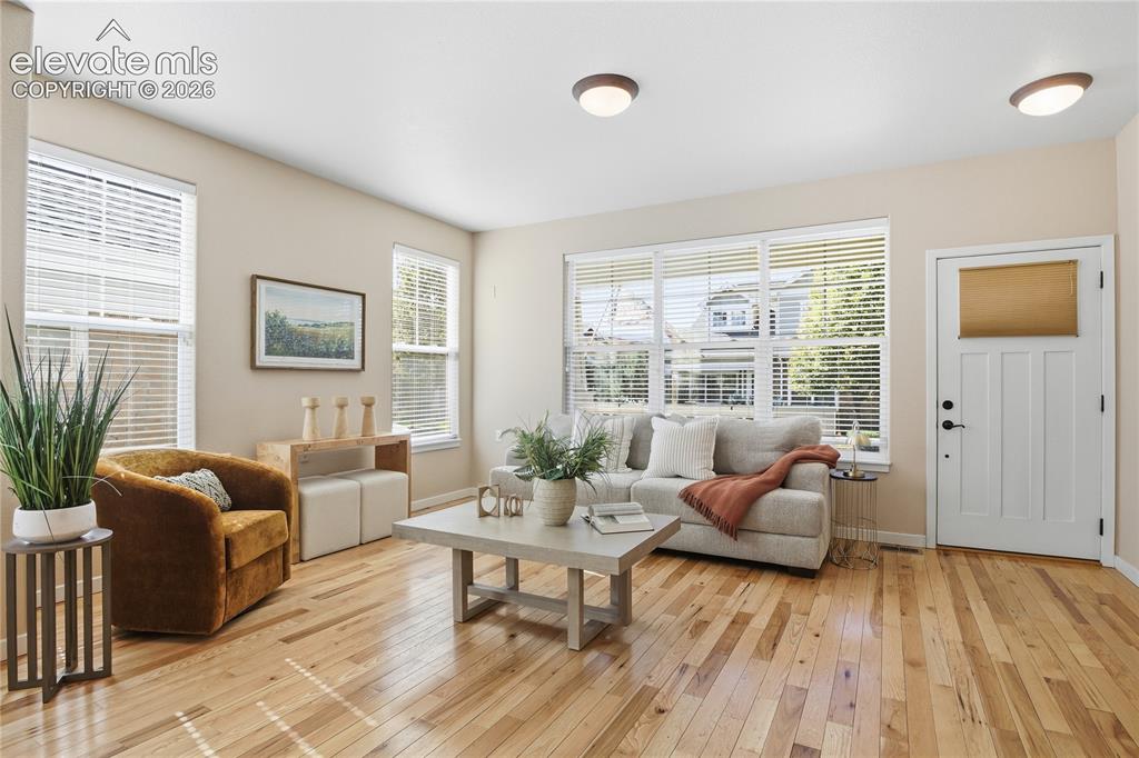 Image 6 of 27: Hardwood flooring, multiple windows with blinds, white panel door with fros