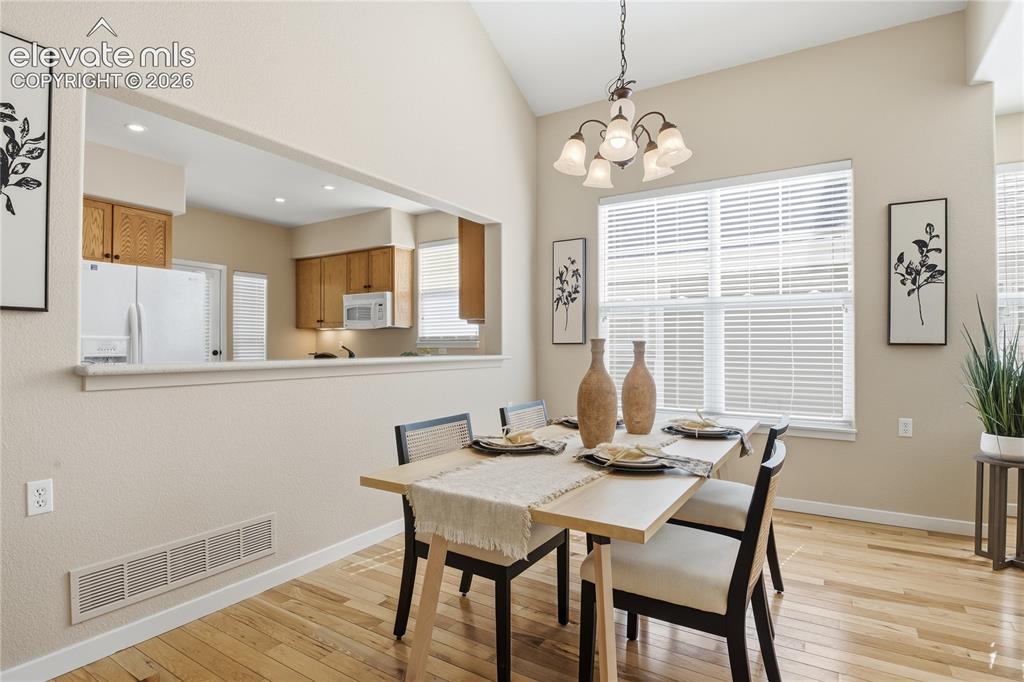 Image 7 of 27: Vaulted ceiling, open pass-through to kitchen, wood-finish flooring, multi-