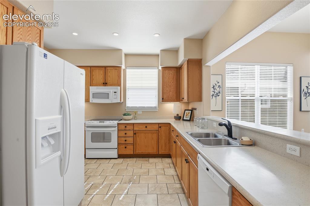 Image 8 of 27: Kitchen featuring wood cabinetry, solid surface countertops, a double basin