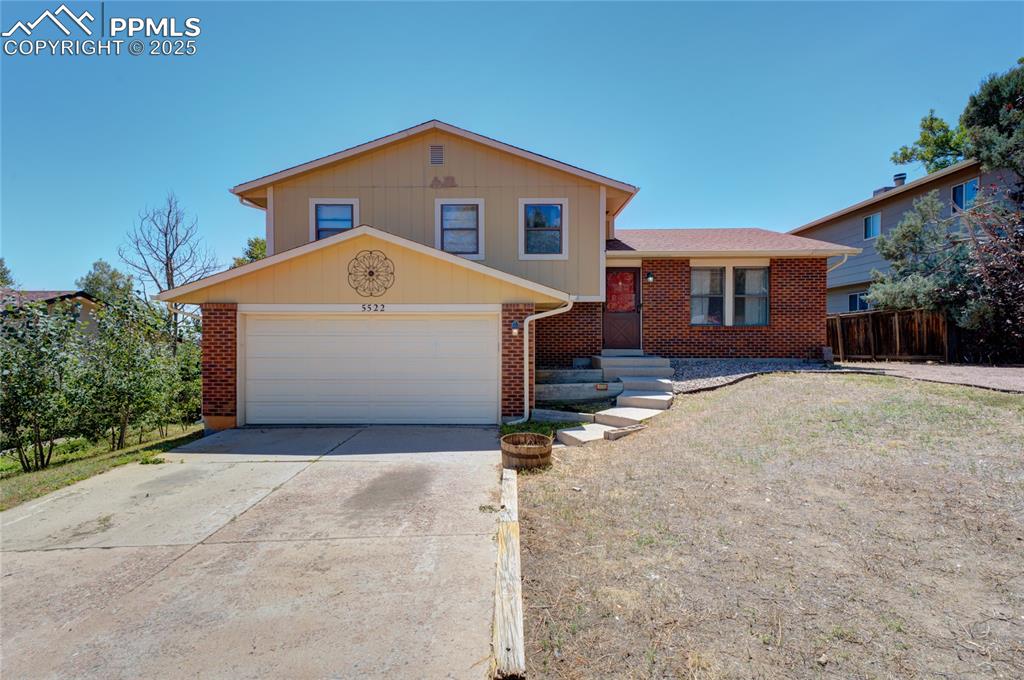 Caption: Tri-level home featuring brick siding and driveway