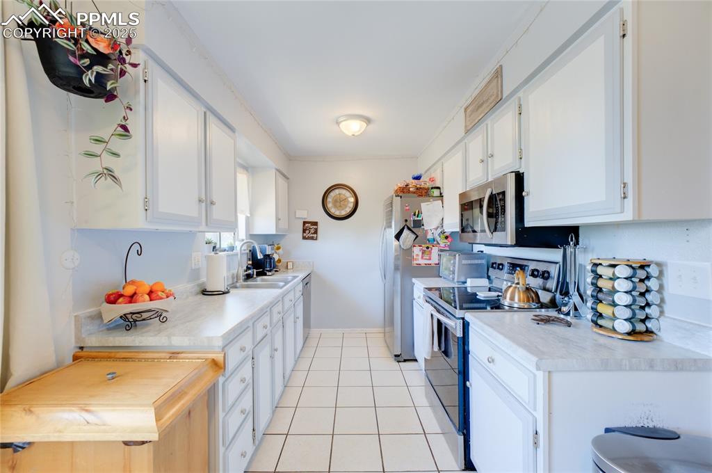 Image 11 of 35: Kitchen with stainless steel electric range oven, white cabinetry, light co