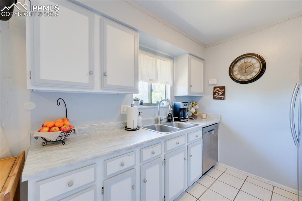 Image 12 of 35: Kitchen with white cabinetry, light countertops, light tile patterned floor