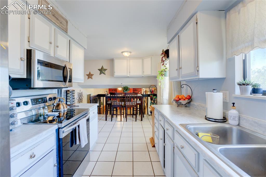 Image 13 of 35: Kitchen with white cabinets, stainless steel appliances, light countertops,